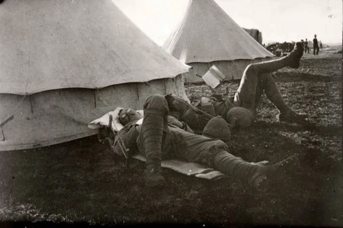 Soldiers resting beside a row of tents