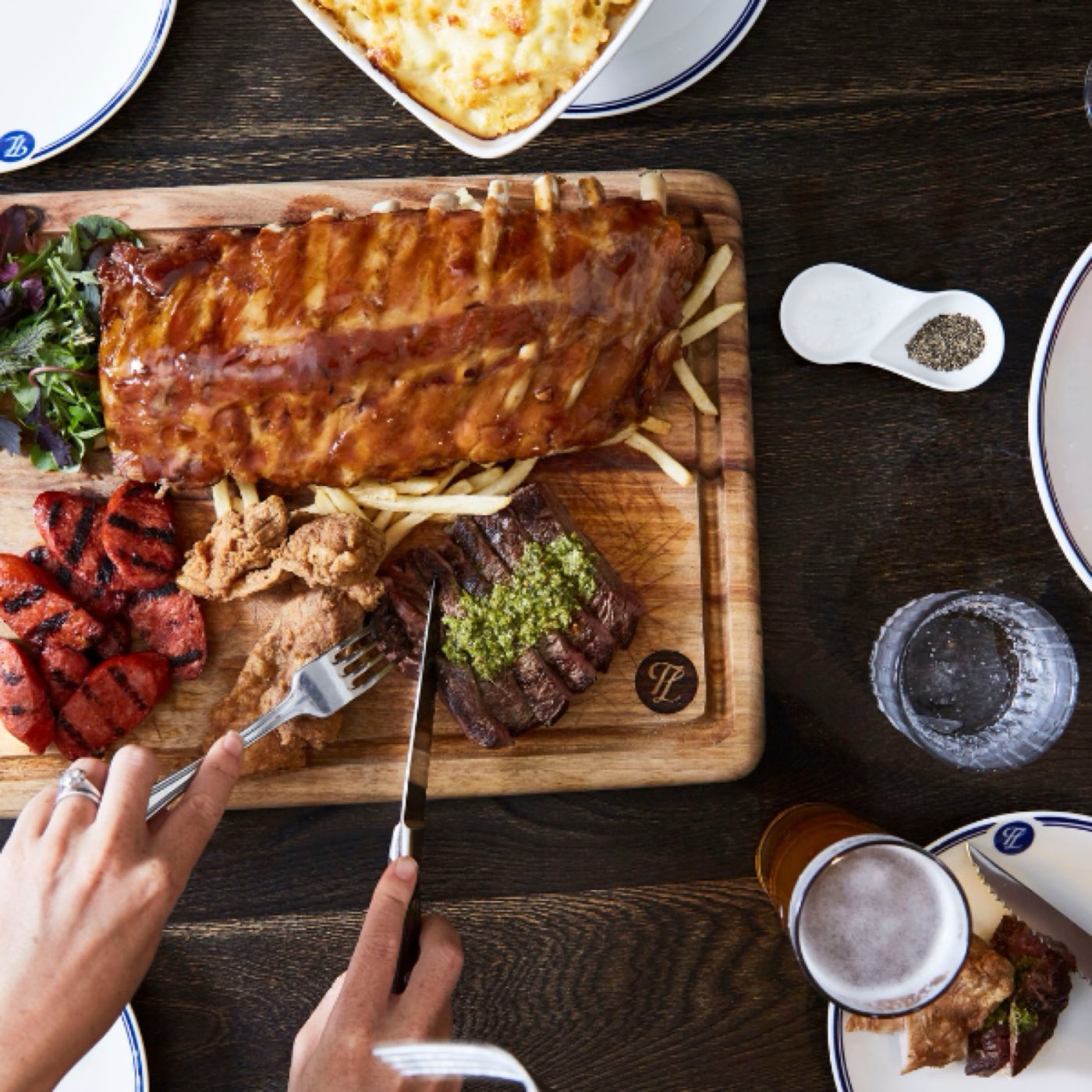 A share board of ribs and steak being carved