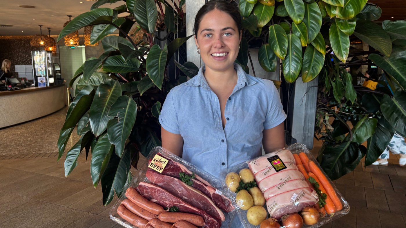 A staff member holding two meat trays